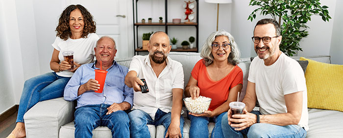 Group of middle age friends smiling happy watching film at home.