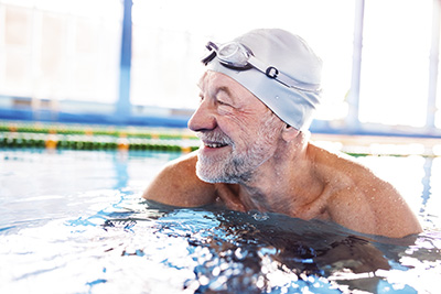 Older gentleman swimming in an indoor pool.