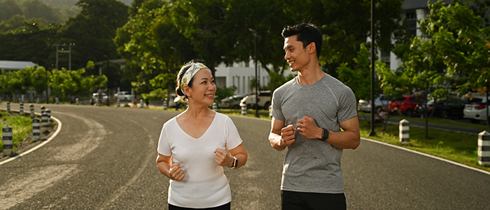 Energetic mature woman and young man jogging in the park. Fitness, sport and healthy lifestyle concept