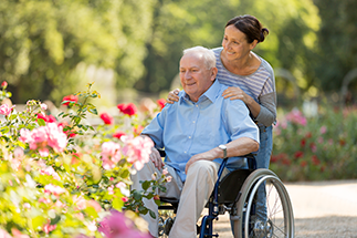 caregiver and man in wheelchair at the garden