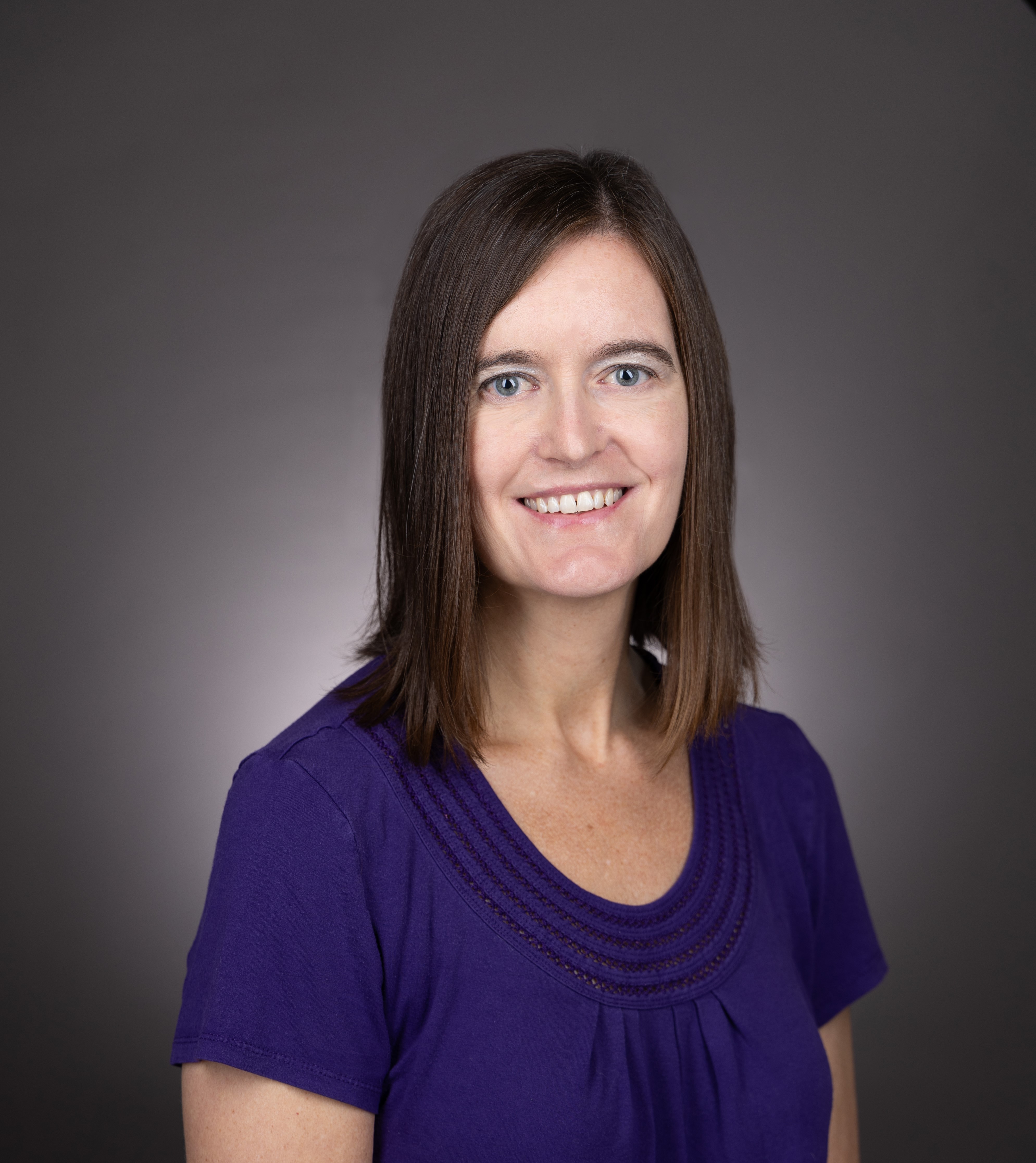 Jessica Koran-Scholl, PhD in a purple blouse with dark gray background