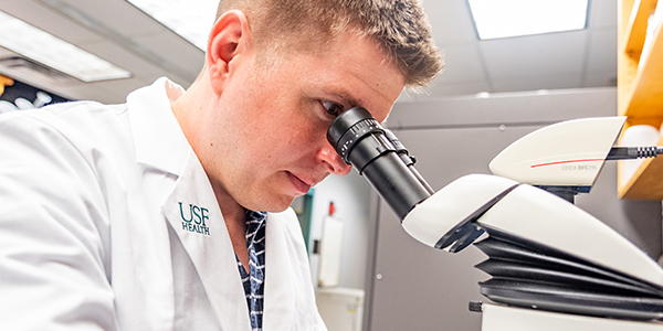 PhD student looks in microscope
