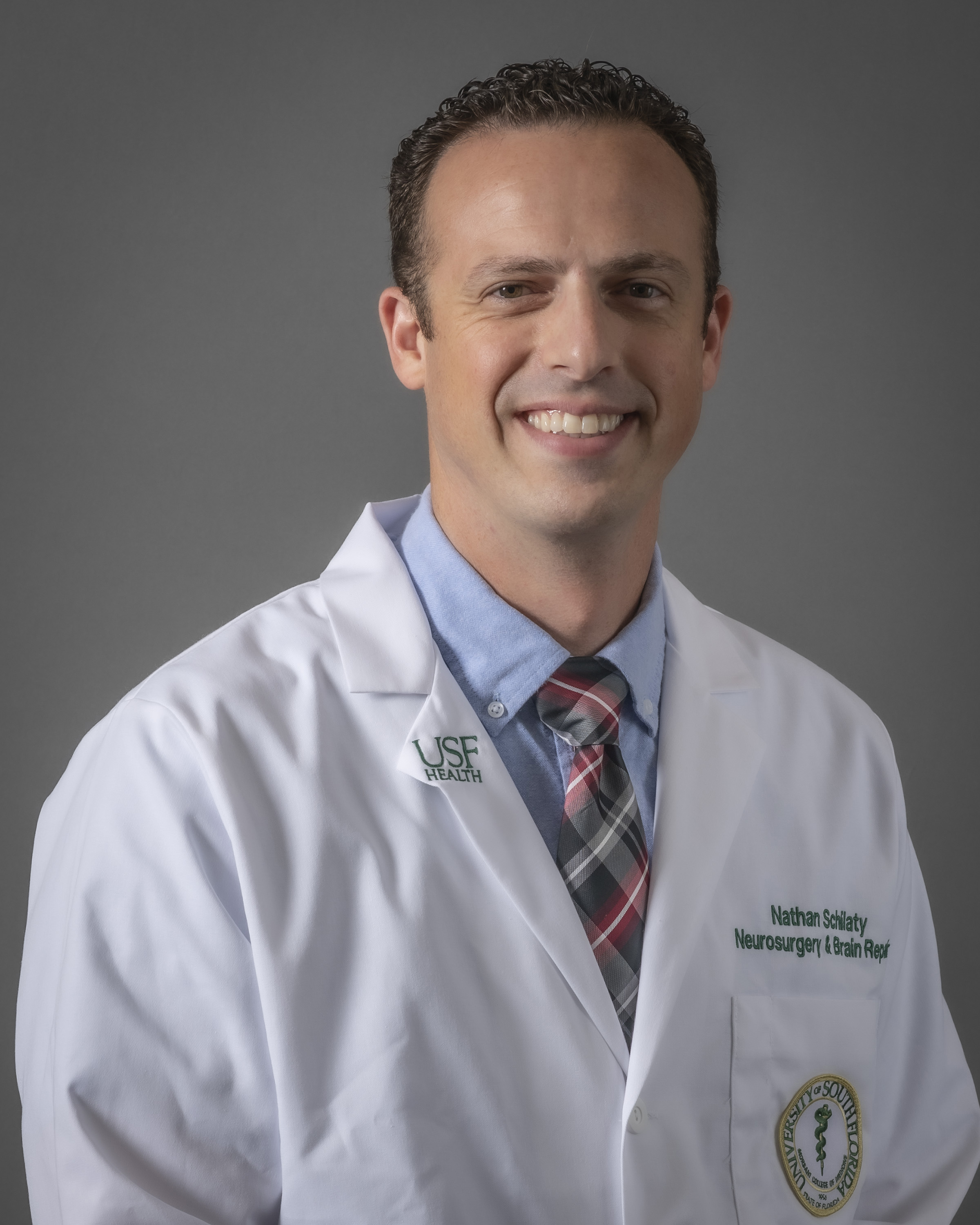 Headshot of Dr. Nathan Schilaty in a medical white coat for USF Health Neurosurgery