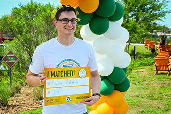 USF Health Match Day 2024, Medical Student holds sign revealing where they have matched for medical residency
