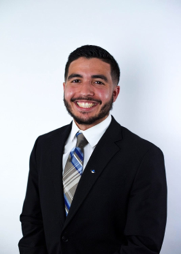 Samir Nacer, USF Health Pathology Resident in a black suit and multi-colored striped tie