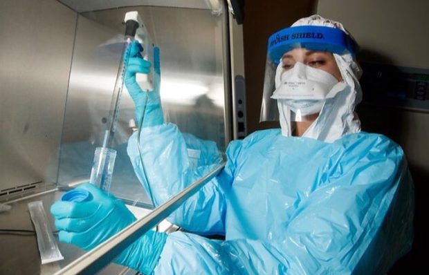 lab person in protective suit working with a pipette