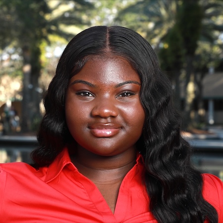 A woman with dark hair wearing a red shirt smiles for a picture