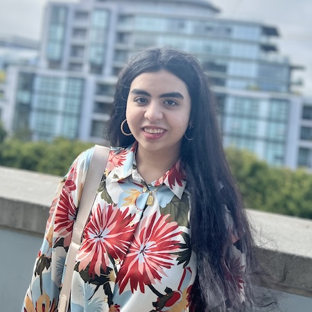 A woman with long, dark hair smiles in a colorful flora blouse