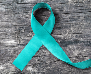 Teal awareness ribbon on a wooden surface, symbolizing sexual assault awareness.