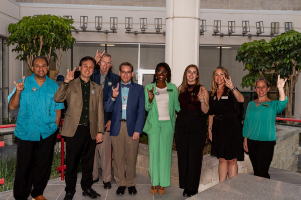 COPH Alumni posing together and holding up the "Go Bulls!" hand symbol