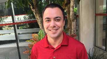 A headshot of Billy Swankie, MSPH, smiling at the camera. He is wearing a red shirt.