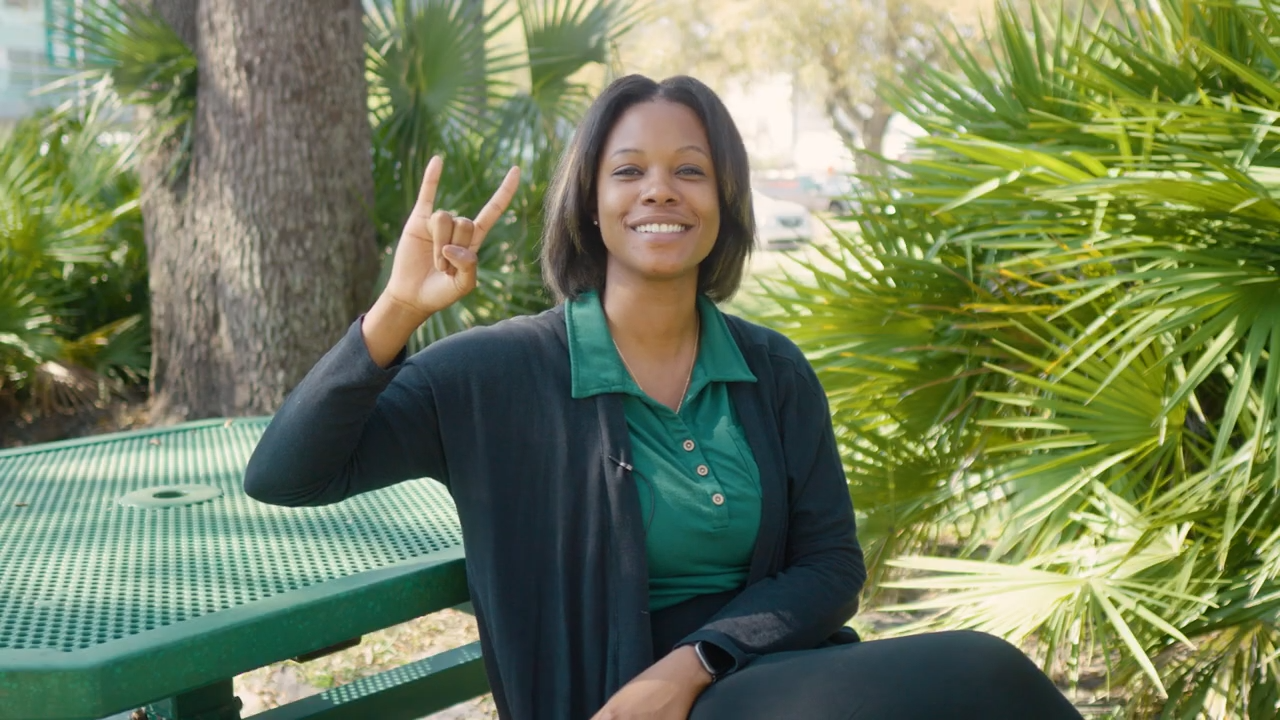 A student holding up the “Go Bulls!” hand symbol