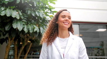 An undergraduate student smiles while walking through the atrium of the college of public health building. 