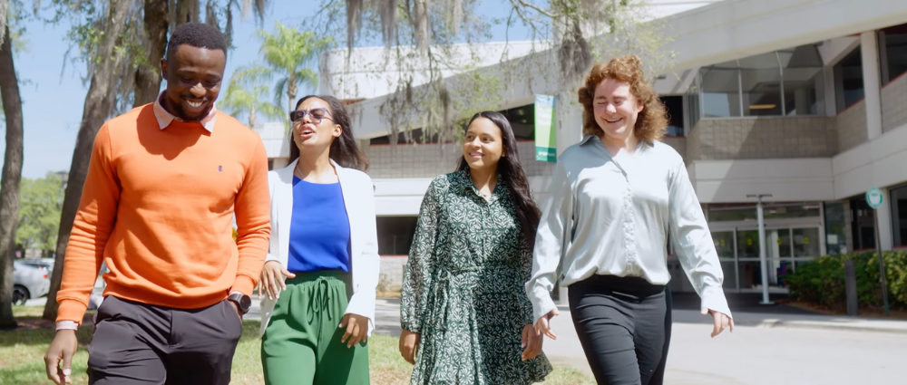 A group of students walking, talking, and smiling in front of the COPH building