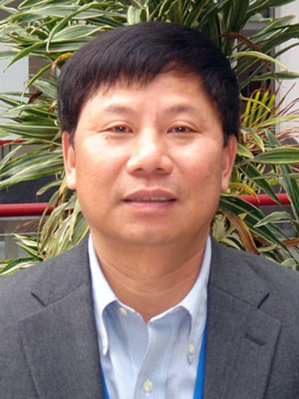 Headshot of Dr. Henian Chen, a man in a suit and tie, standing in front of a green plant.
