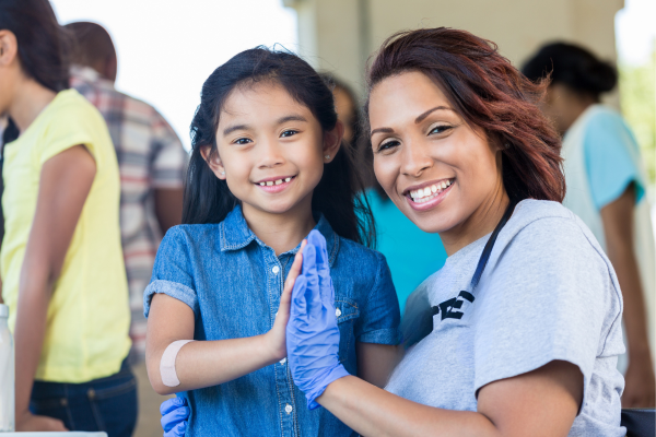 A public health professional giving a high-five to a child