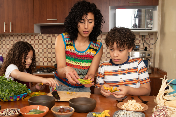 A mother and her two children preparing food in a kitchen