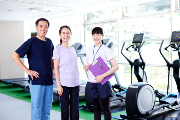 Three people standing in a gym posing for a picture