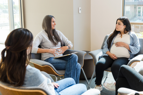 A group of pregnant people and new mothers having a discussion.