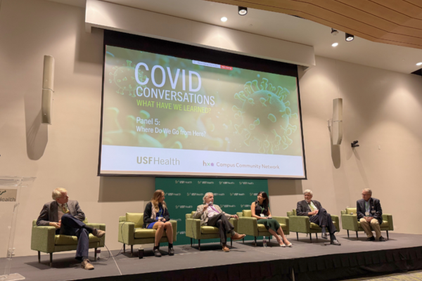 Researchers sitting in front of a presentation screen displaying research about a virus