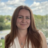 A headshot of Nataliya Kuzmin standing in front of a nature landscape backdrop.
