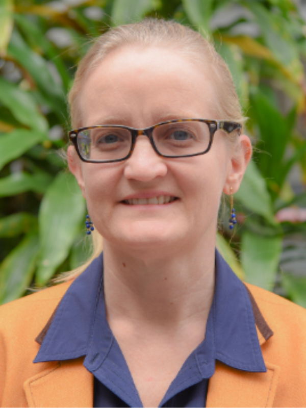 A headshot of Dr. Amy Stuart posed in front of greenery