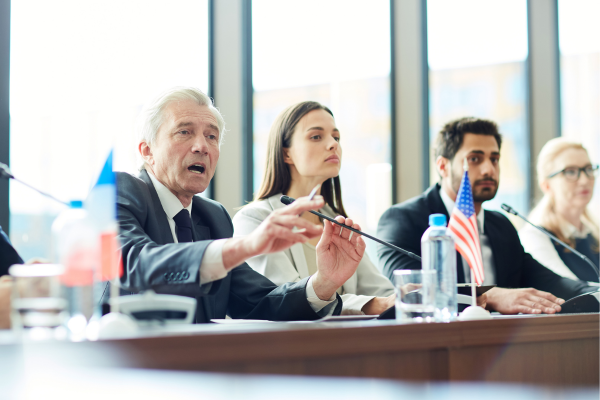 A group of people sitting at a conference table with microphones