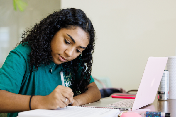 A person in a green shirt working on their laptop