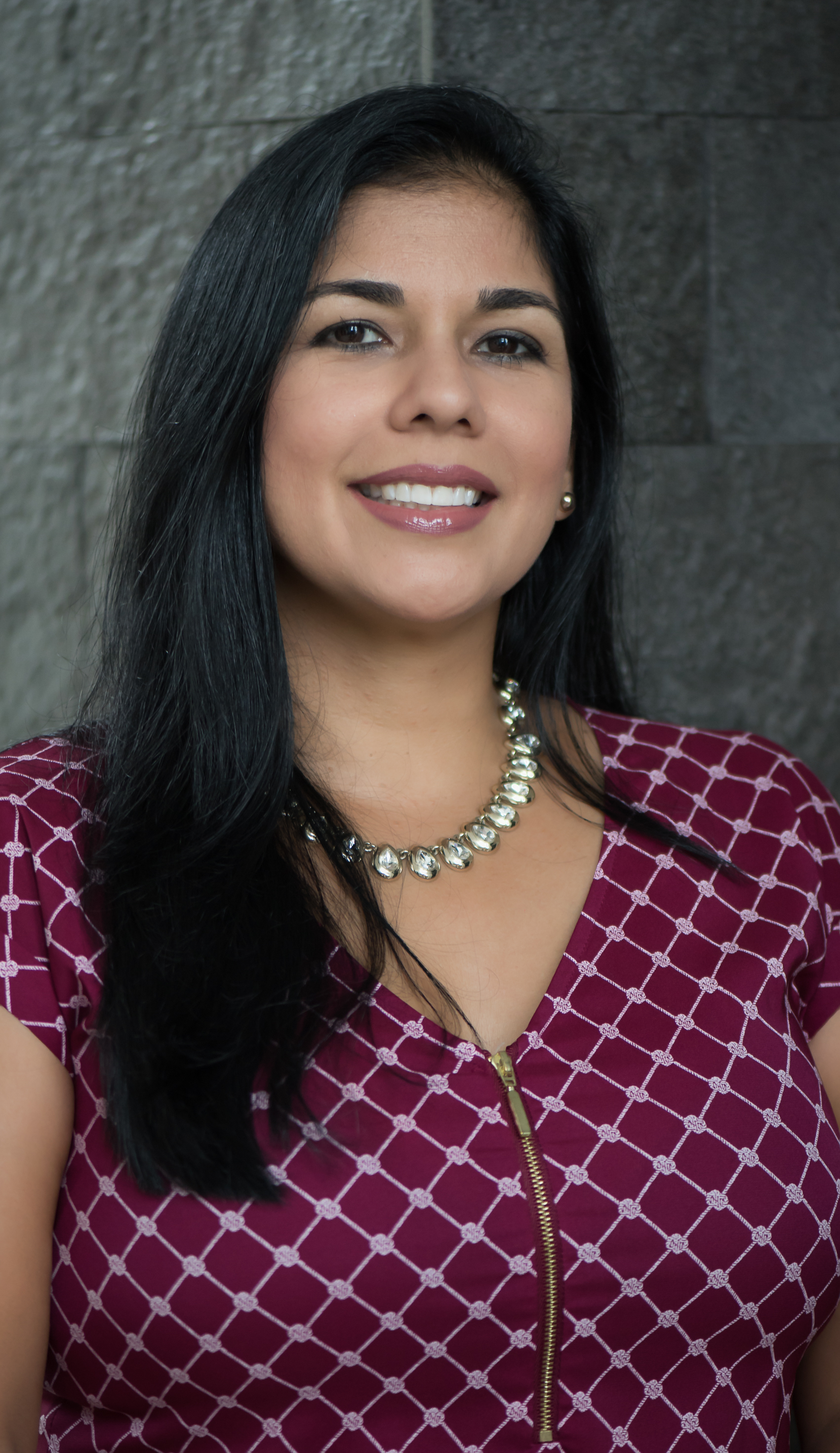 Headshot of Arlene Calvo in front of a grey brick wall