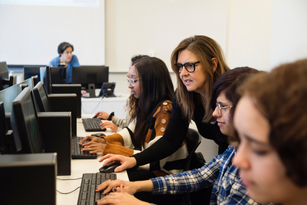 A woman helping a student working on a desktop computer.