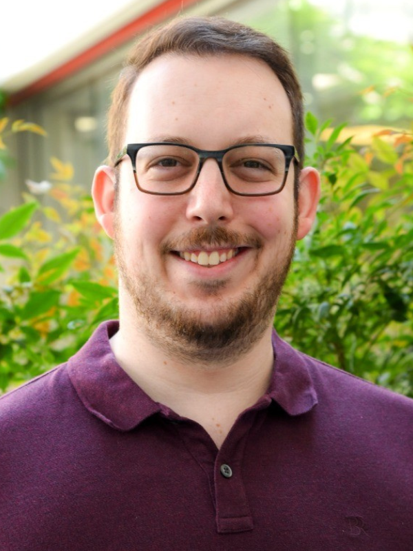 Headshot of Neil Bleiweiss in front of greenery