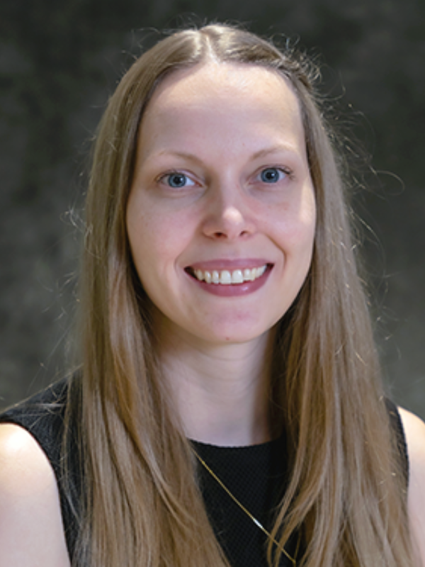 A headshot of Dr. Judith Rijnhart in front of a dark grey backdrop. She is smiling and wearing a black top.