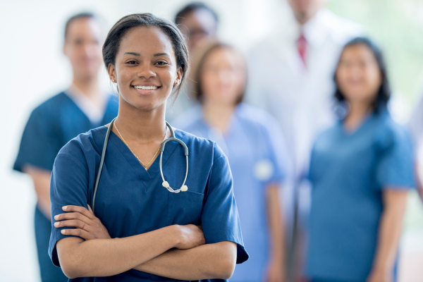 A woman in scrubs standing in front of a group of nurses