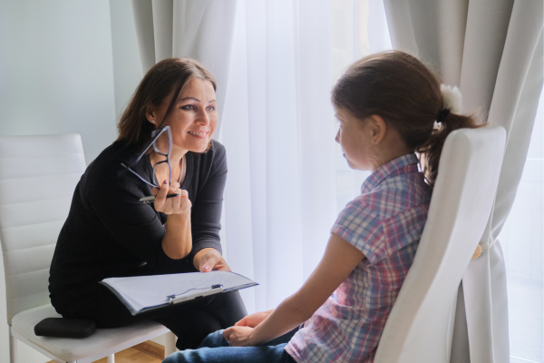 A psychologist talking to a child in front of a window