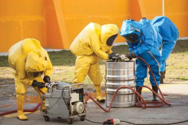 A group of people in hazmat suits working on a barrel