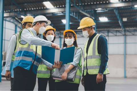 A group of people in safety gear standing in a warehouse