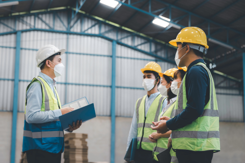 A group of people in safety gear standing in a warehouse