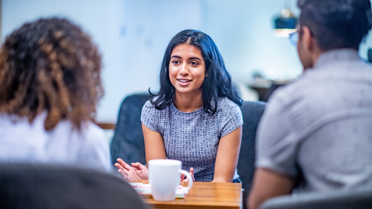 A person sitting at a table talking with two other people