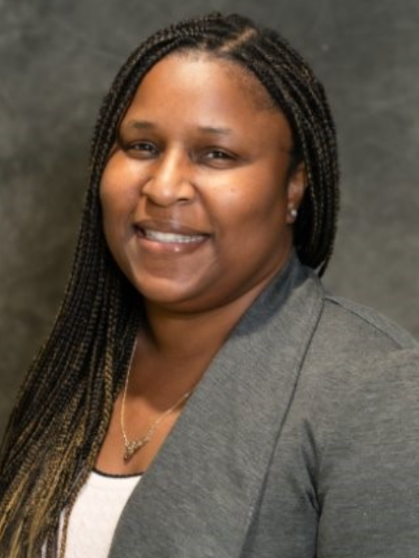Headshot of Joni Williams smiling in front of a grey backdrop