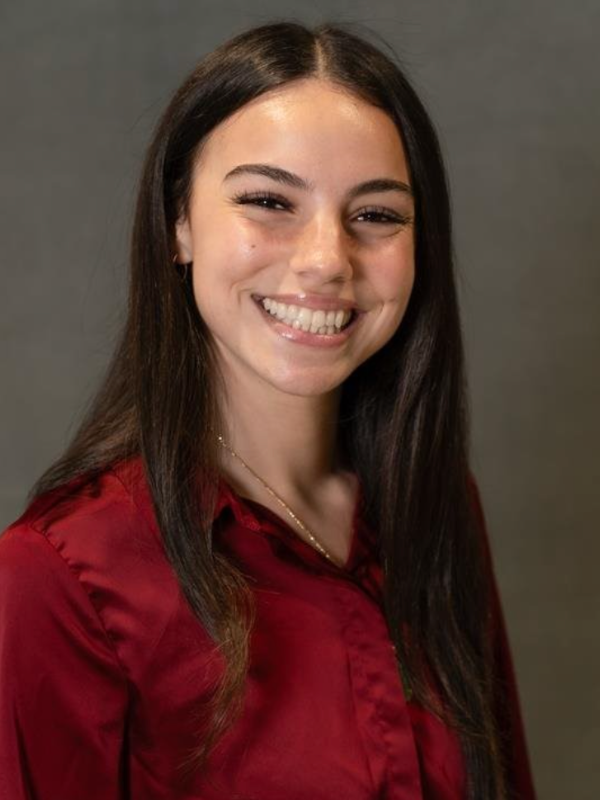 Headshot of Kristal Furnaro smiling in front of a grey backdrop