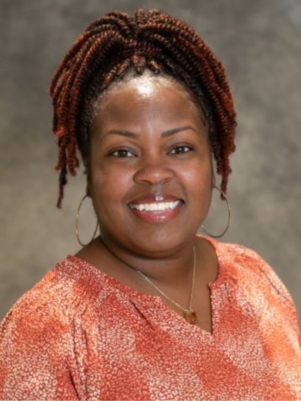 Headshot of Niyla Peters-Salter smiling in front of a grey backdrop