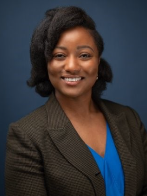 Headshot of Renne Wallace smiling in front of a navy blue backdrop