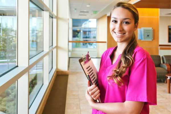 A public health student smiling and holding a clipboard