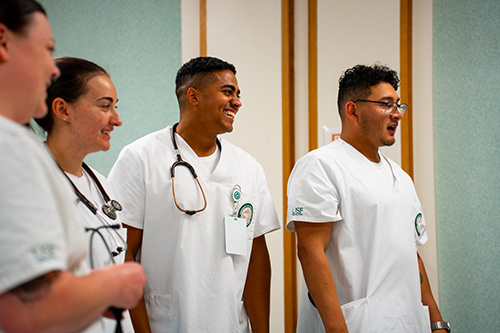 four nursing students in scrubs smiling 