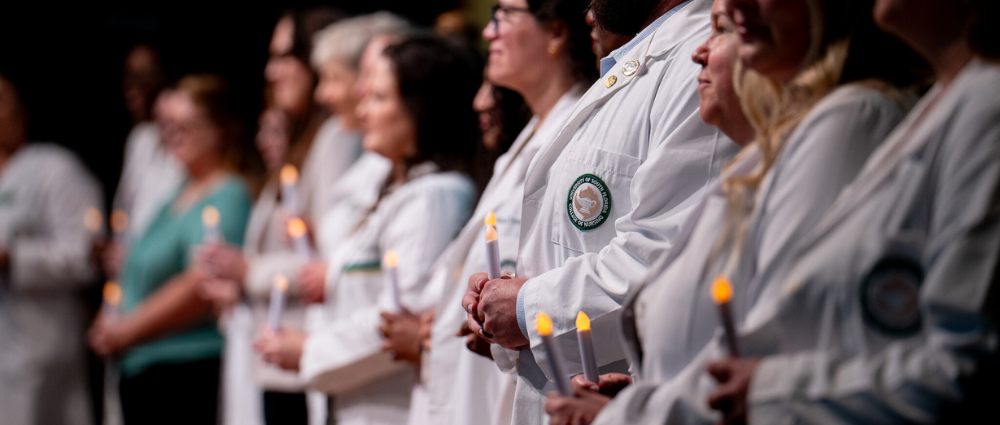 nursing faculty with white coats holding candles