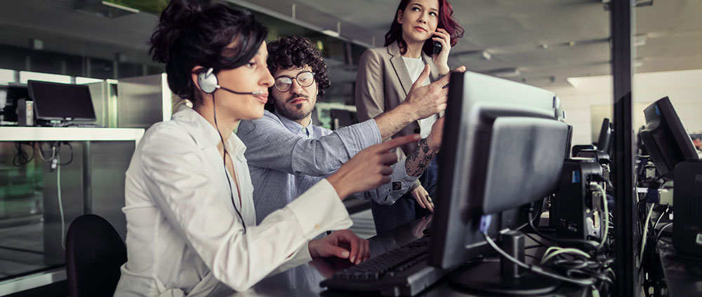 Team of three people using computers and telephones together