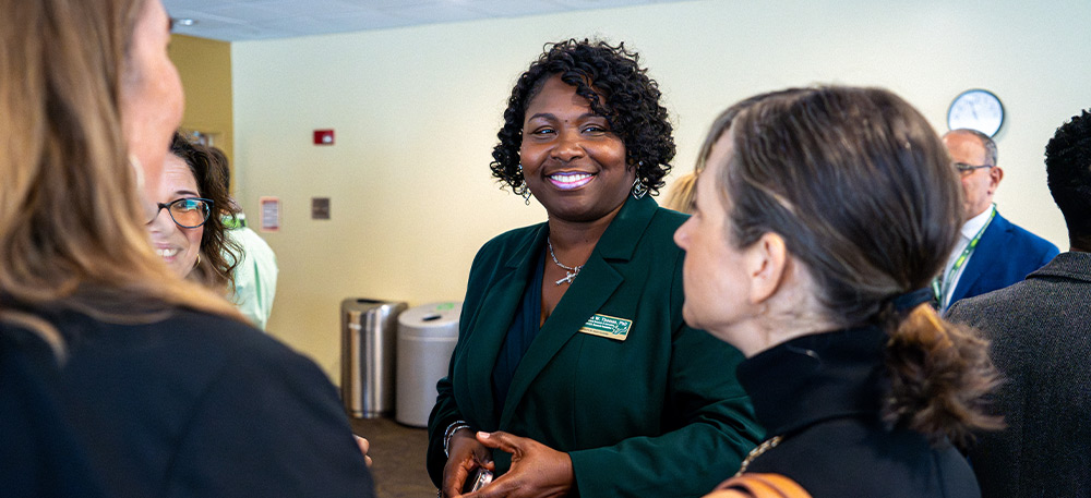 Small group of faculty members standing together in business attire, having a discussion.