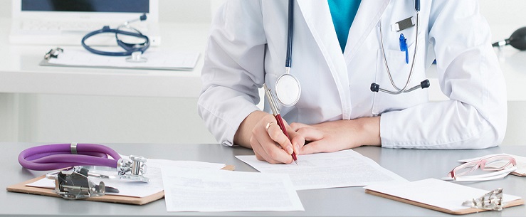 Close up of a doctor sitting at a desk, signing a document