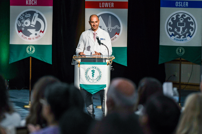 Dr. Peter Chang speaking at a podium at the USF Health Morsani College of Medicine White Coat Ceremony in 2023