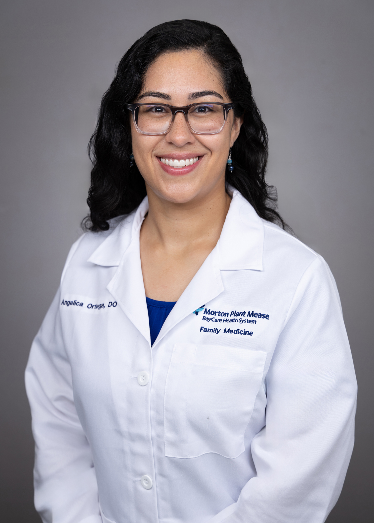 Angelica Ortega smiling wearing a medical white coat